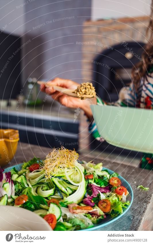 Woman putting quinoa in salad woman cook vegan kitchen healthy food culinary ingredient homemade product lunch vitamin cucumber vegetable add appetizing utensil