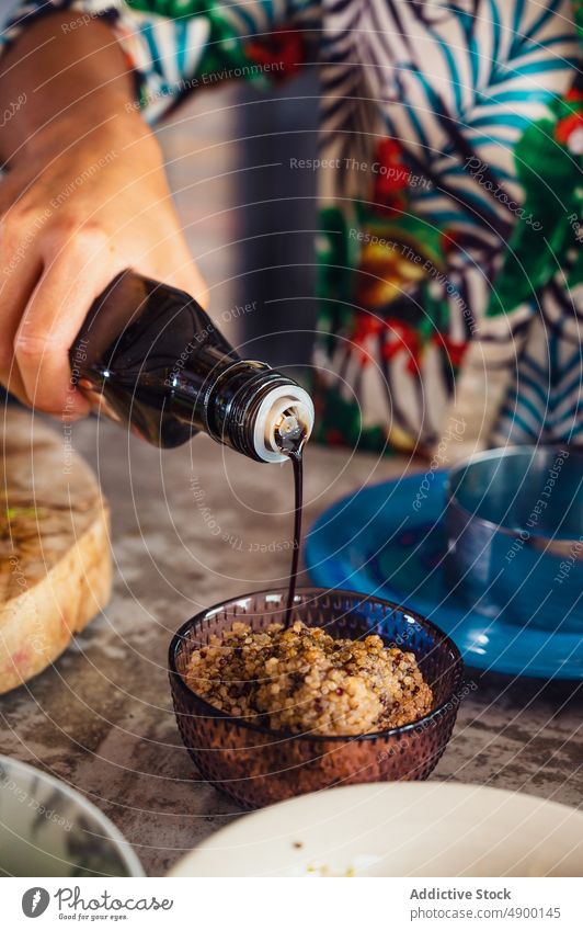 Crop woman adding soy sauce into quinoa cook pour prepare bowl kitchen vegan healthy food home culinary cuisine ingredient dish fresh organic lunch recipe