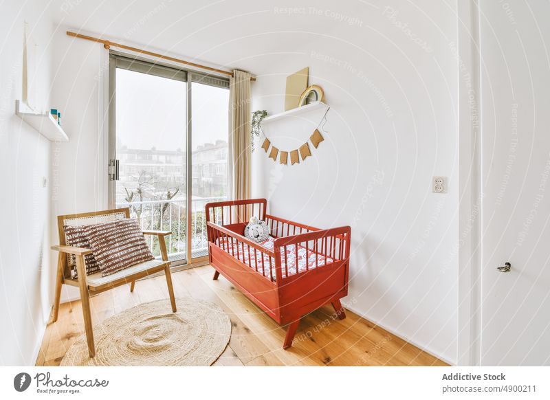 Interior of a room with a wooden crib indoor baby interior modern design red wall apartment bear cozy bed home white bright decoration carpet chair comfortable
