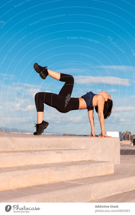 Positive woman exercising on street sportswoman exercise training workout healthy lifestyle practice crab hobby leg raised stamina content body figure flexible