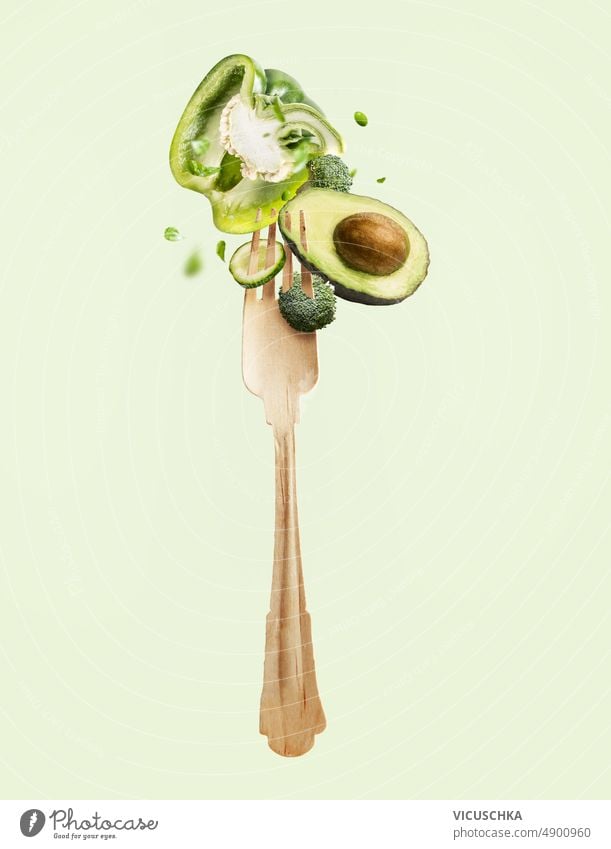 Flying fork with green vegetables salad ingredients flying food levitation dieting detox bell pepper avocado broccoli cucumber backdrop front view background