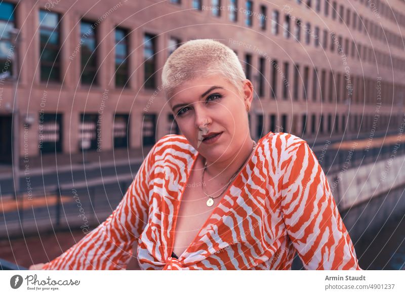 power and beauty: portrait of a young woman with short blonde hair on a bridge in Berlin studio serious confident strong powerful business piercing jewelry