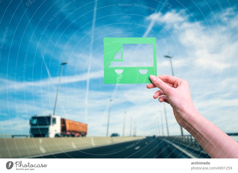 Hand holds green logistics symbol against highway transport eco climate concept ecology truck future conservation delivery travel energy environment