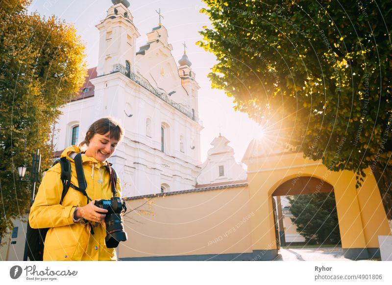 Pinsk, Brest Region, Belarus. Young Woman Tourist Lady Photograph Taking Pictures Near Cathedral Of Name Of The Blessed Virgin Mary. Famous Historic Landmarks. Sun Sunshine In Autumn Sunny Day.