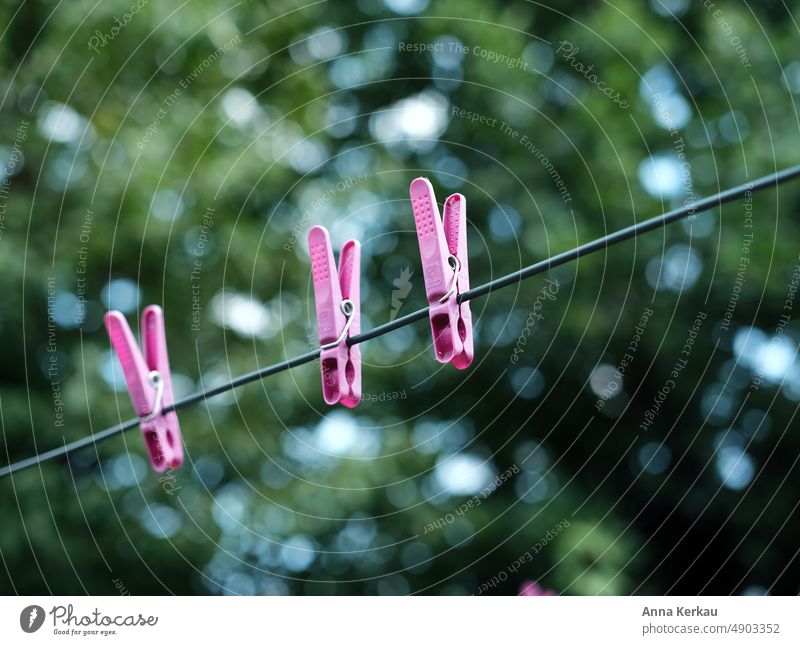 Three pink clothespins on the clothesline against green background Clothes peg Laundry Washing Washing day Hang Living or residing Photos of everyday life