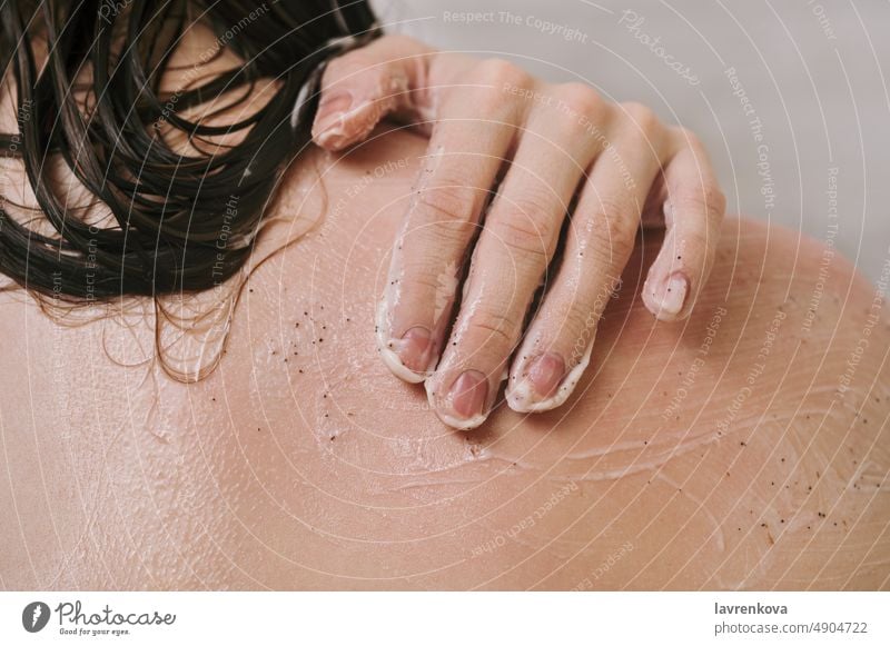Faceless shot of woman using narutal scrub on her shoulder in the shower person skin hand beauty hygiene beige fingers treatment closeup healthy skincare smooth