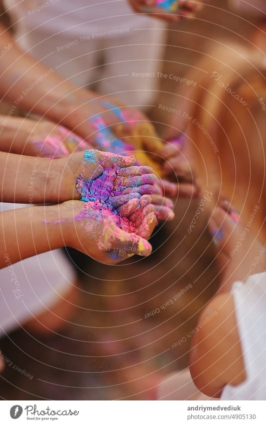 hands of children and adults in the colors of the hall. family having fun with holi paints outdoors. Holi color festival. son young mother portrait little boy
