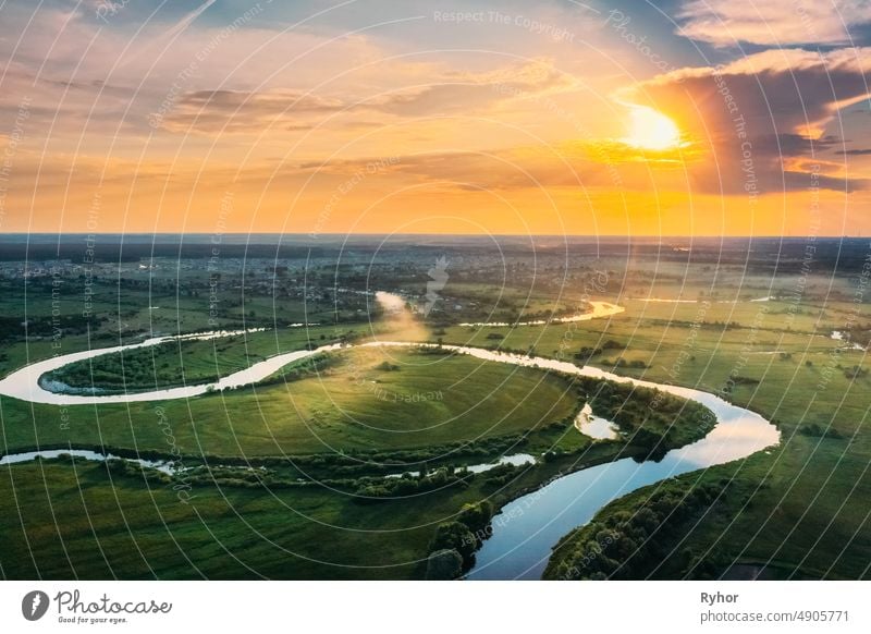 Aerial View. Beautiful Sunset Sun Sunshine Above Green Forest, Meadow And River Landscape In Sunny Evening. Top View Of European Nature From High Attitude In Summer Sunrise. Bird's Eye View. Belarus.