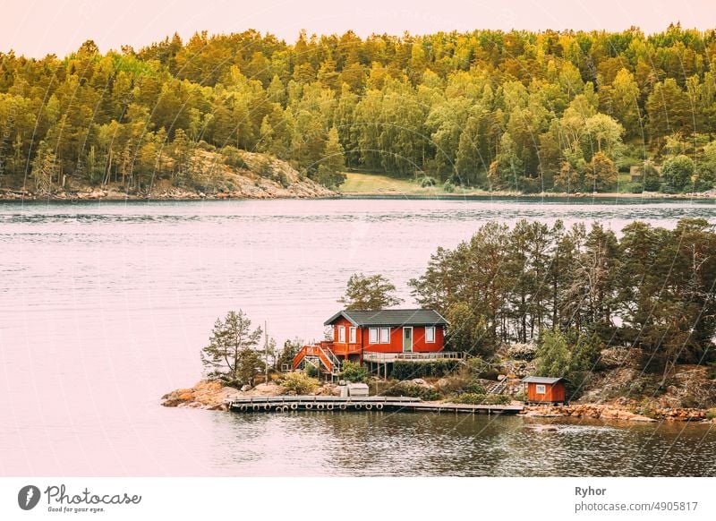 Sweden. Many Beautiful Red Swedish Wooden Log Cabin House On Rocky Island Coast In Summer. Lake Or River Landscape apartment archipelago bathhouse beautiful