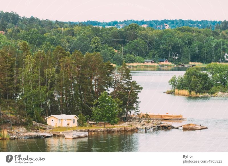 Sweden. Beautiful Swedish Wooden Log Cabins Houses On Rocky Island Coast In Summer Day. Lake Or River Landscape apartment archipelago bathhouse beautiful