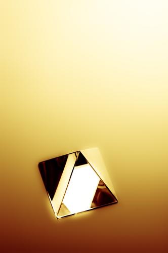 Abstract image of a crystal pyramid with gold yellow rays of bright light. 3d abstract beam blur blurry concept conceptual condensation dark defocused design