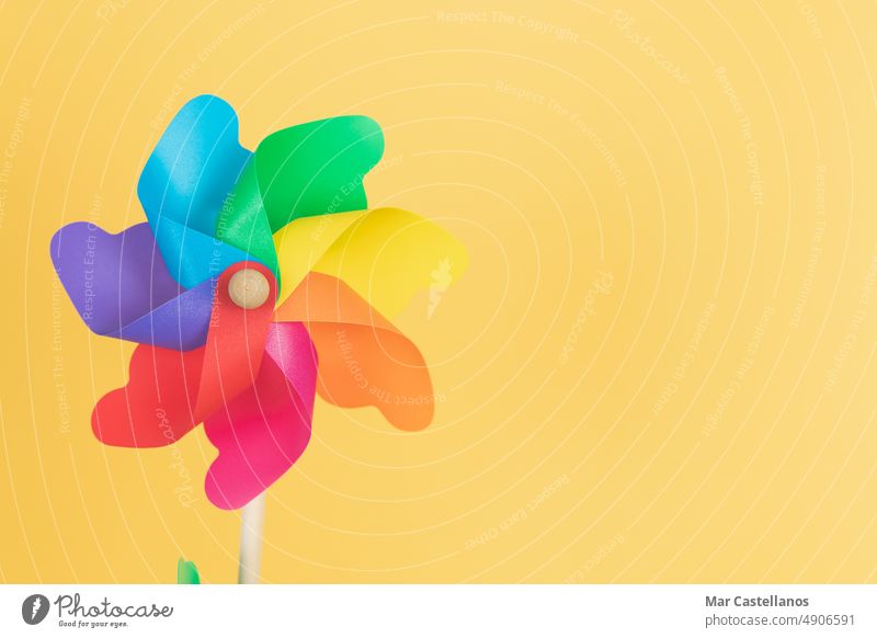 Coloured pinwheel on yellow background. Copy space. rainbow lgtbq movement copy space green toy children party unfocused decoration rotation colour plastic