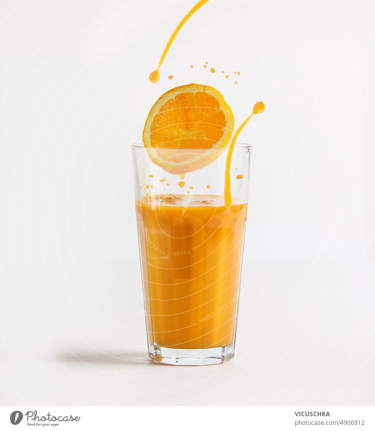 Orange juice in glass with orange slice and splashing liquid at white background. orange juice healthy refreshing beverage vitamins citrus fruits front view
