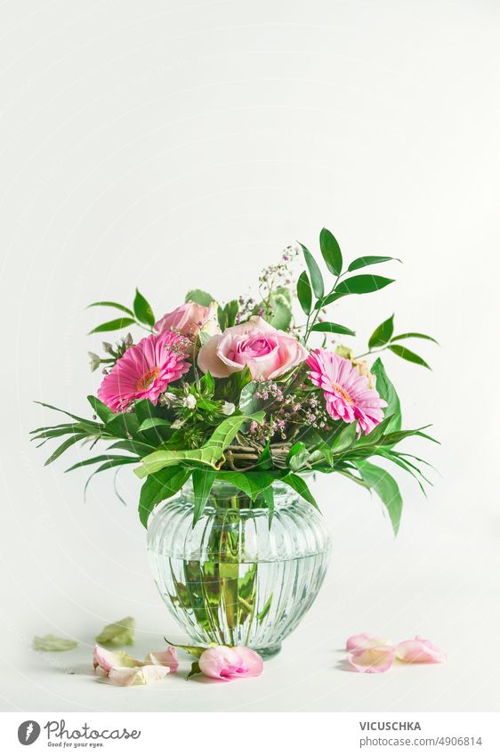 Beautiful summer flowers bouquet with roses and gerbera flower and green leaves in glass vase at white background beautiful front view bloom blossom bunch