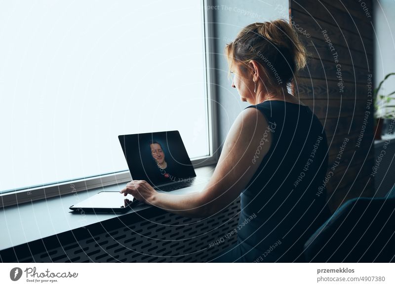 Businesswoman having business video call on laptop in office. Mature busy woman remotely working from office. Female manager using digital devices. Remote communication. Video calling. Remote work