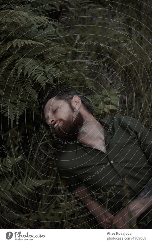 man in a forest green portrait Portrait photograph Portrait of a man bearded Cigarette smoking fern Forestry laying Laying Down face eyes closed Tattooed Adults