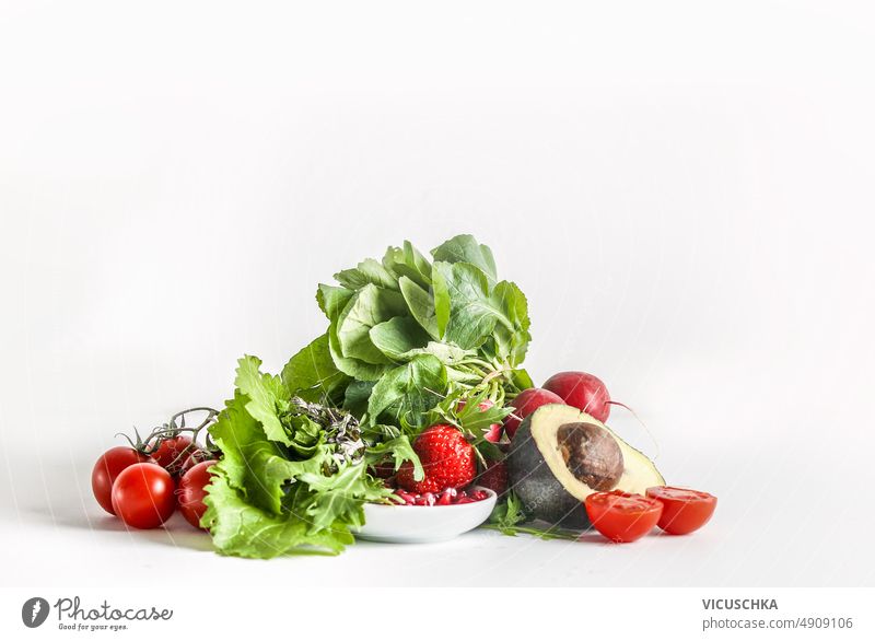Heap of healthy salad ingredients at white background heap lettuce tomato avocado pomegranate seeds raspberry front view dinner food fresh green lunch nutrition