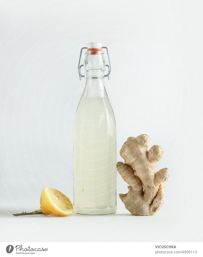 Bottle with homemade ginger ale, lemon and gingerroot at white background bottle front view fermented healthy beer beverage delicious drink fresh glass natural