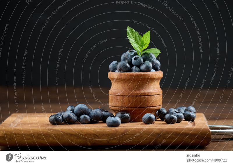 Ripe blueberries in a wooden bowl on the table, black background blueberry food fresh fruit raw ripe closeup juicy vegetarian sweet tasty ingredient antioxidant