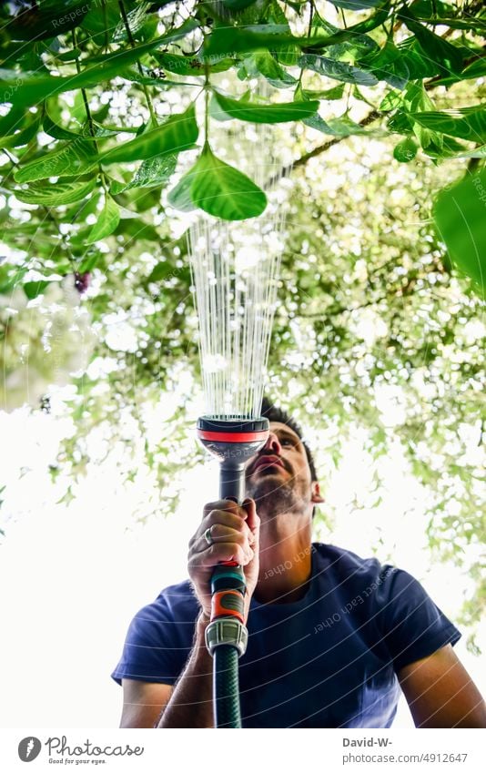 Man watering flowers in garden Garden soak Water hose Summer dry spell water consumption Gardening plants Cast Gardener