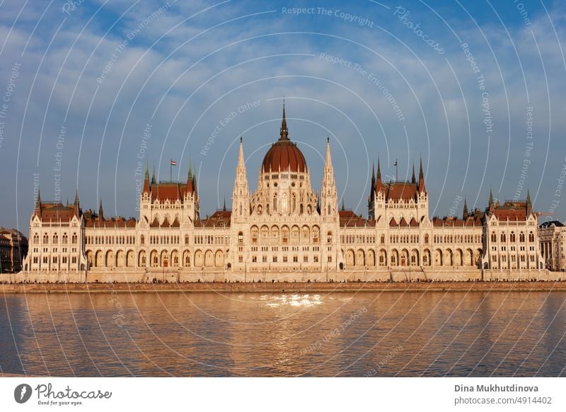 Hungarian Parliament Building in Budapest reflected in the water of Danube, photographed on sunny day with blue sky. Domed Neo-Gothic style architecture. Famous landmark for sightseeing in Hungary. Postcard view.