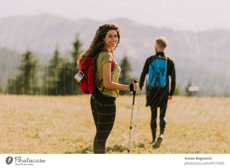Smiling couple walking with backpacks over green hills active activity adults adventure backpacker backpacking boyfriend caucasian countryside curly female