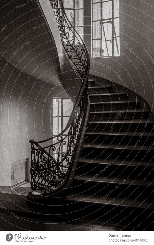Curved old-fashioned staircase with fancy railing Stairs stairwell Old heritage Vintage Classic Historic Black & white photo Grain Window stylish Architecture