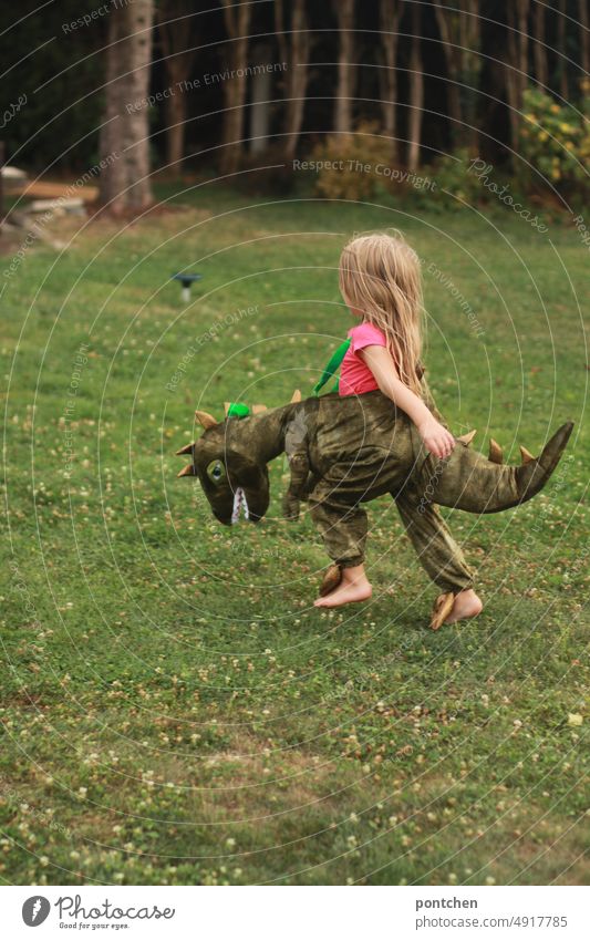 A small child dressed as a dinosaur runs through a garden. Play Child Dinosaur cladding Costume Garden Walking Playing carnival Carnival Infancy Girl