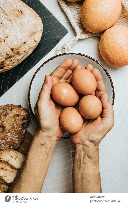 Old hands preparing a organic and healthy meal with Sourdough bread, eggs and fruit juice. New habits, rustic ambient, taking care of yourself. Bakery and cooking concept. Bio real food