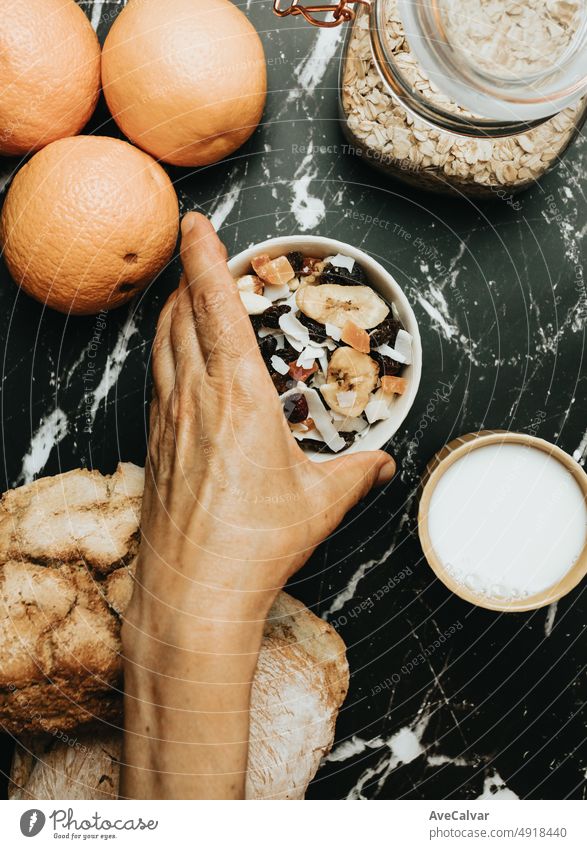Old hands preparing a organic and healthy meal with Sourdough bread, dehydrated fruit and fruit juice. New habits, rustic ambient, taking care of yourself. Bakery and cooking concept. Bio real food