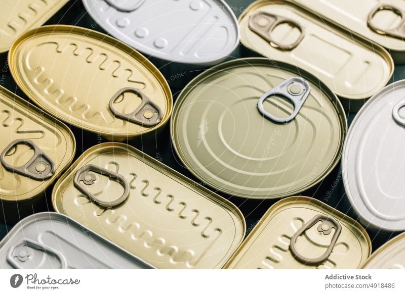 Row of cans on a blue background tin metal tin can food container canned isolated product packaging aluminum conserve blank empty jar steel canister lid object