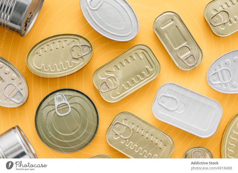 Row of cans on a yellow background tin metal tin can food container canned isolated product packaging aluminum conserve blank empty jar steel canister lid