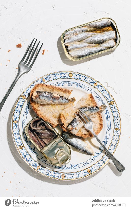 Closeup of a plate of bread with sardines metal tin can conserve open metallic top view food seafood fish canned nutrition background isolated preserve product