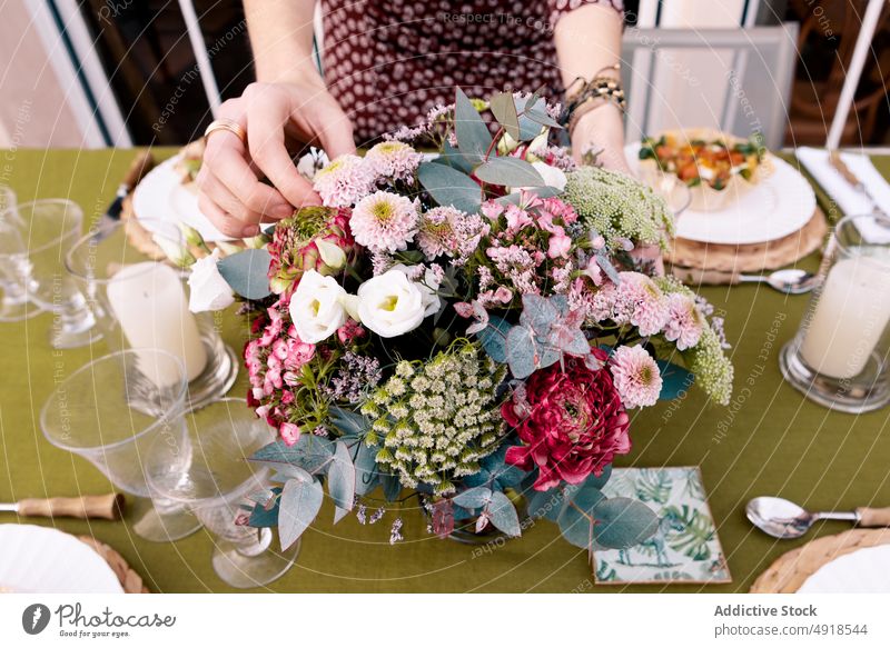 Anonymous woman arranging table together on terrace arrange food flower appetizer banquet spend time spare time tasty plant floral bouquet starter delicious