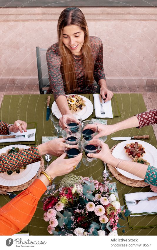 Women clinking wineglasses on terrace women friend toast cheers celebrate drink meeting reunion company salad dinner red wine food alcohol booze spend time