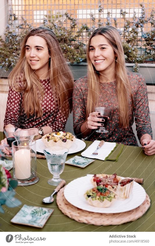 Content women talking during dinner on terrace friend chat speak food red wine spend time celebrate spare time wineglass drink optimist enjoy glad friendly