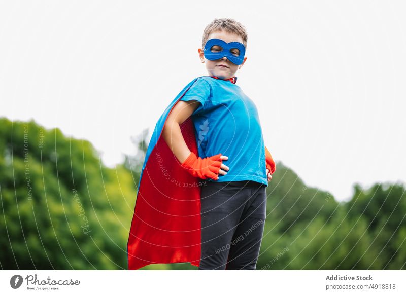 Little superhero with flying cape boy brave summer park pretend play weekend costume sky gray kid confident child male childhood trees protect little cloak