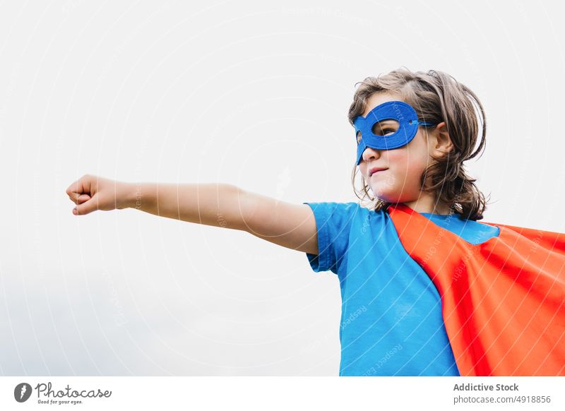 Excited girl in superhero costume in park play tree arm raised power cloudy female cape mask excited summer kid child daytime brave hand raised activity cloak