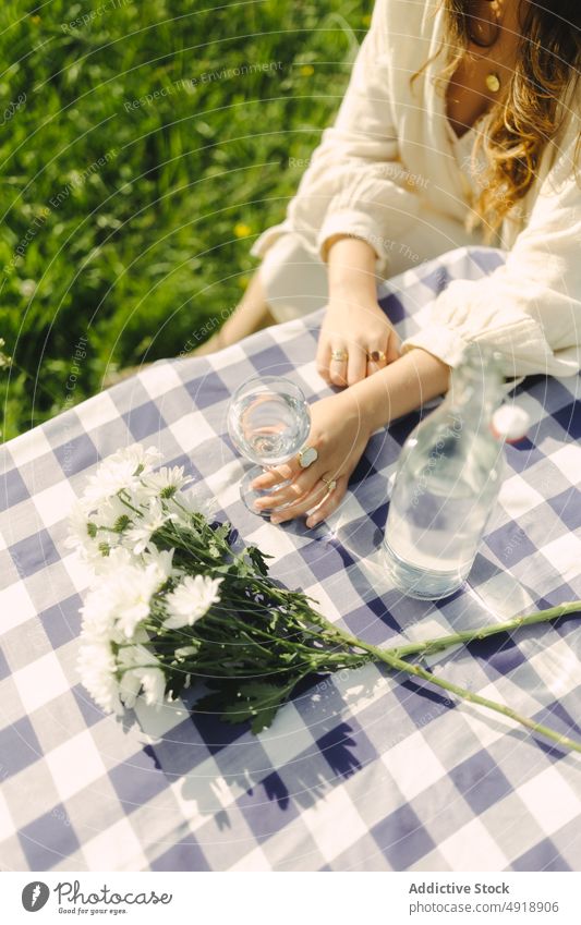 Unrecognizable woman drinking water in goblet in field glass table refreshment beverage countryside nature pastime recreation feminine summer female lady rural