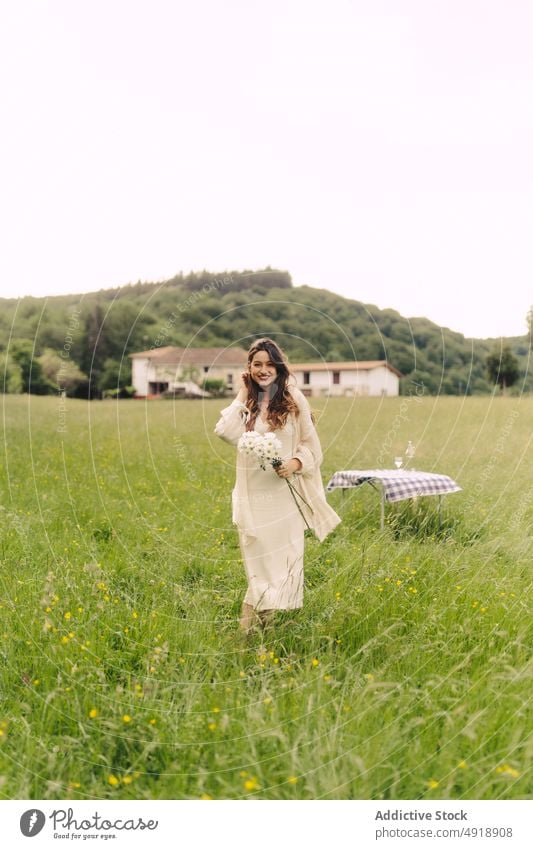 Smiling woman with flowers standing in field bouquet countryside grass recreation summer bunch smile nature pastime feminine table delight floral plant female