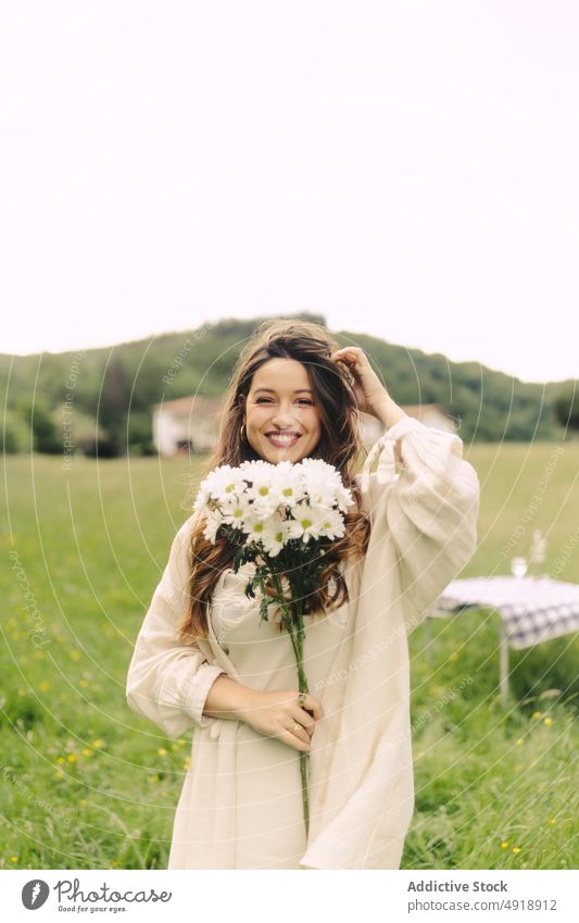 Smiling woman with flowers standing in field bouquet countryside grass recreation summer bunch smile nature pastime feminine table delight floral plant female