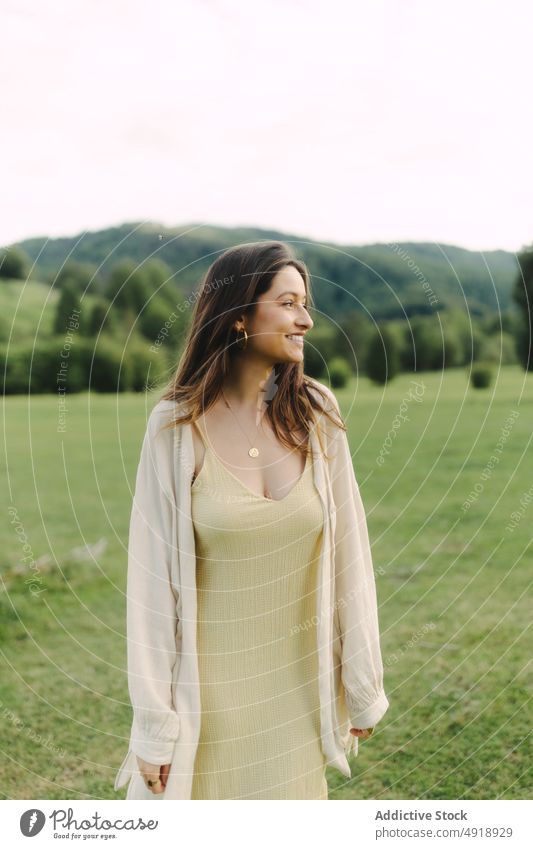 Young smiling woman standing in field in summer countryside delight meadow grass dress glad nature pastime cheerful smile feminine woodland female rural flora