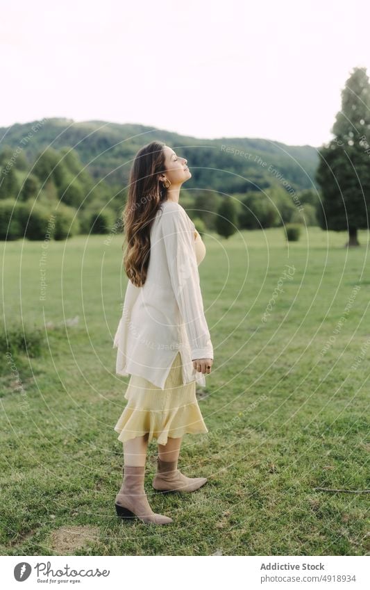 Young woman standing in field in summer countryside meadow grass dress nature pastime recreation feminine woodland female lady rural flora grassy leisure