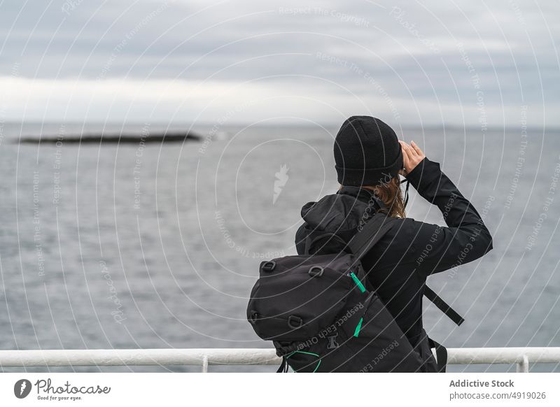 Female photographer on ship deck woman take photo sea coast water memory travel iceland female coat hat backpack boat outerwear shoot dull photography gray