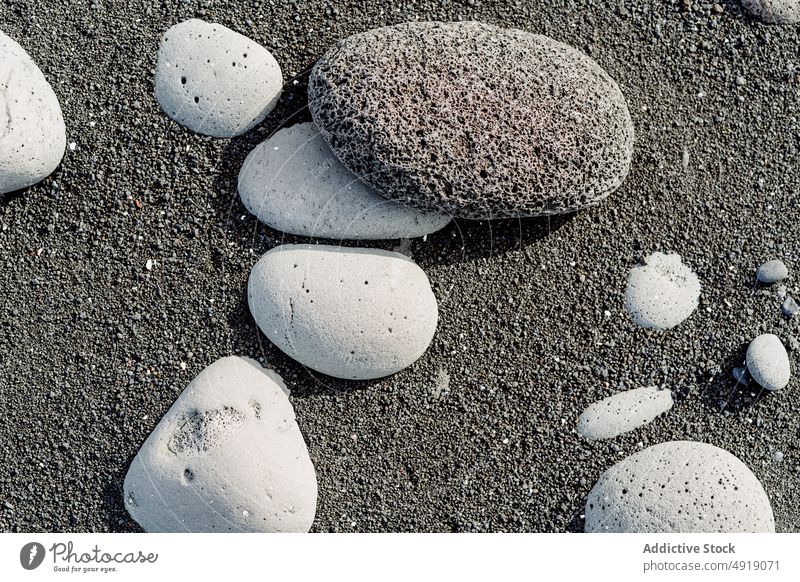 Various pebbles on black sandy shore in sunlight stone beach ash volcanic seashore nature coast mineral geology shape rock iceland natural surface idyllic