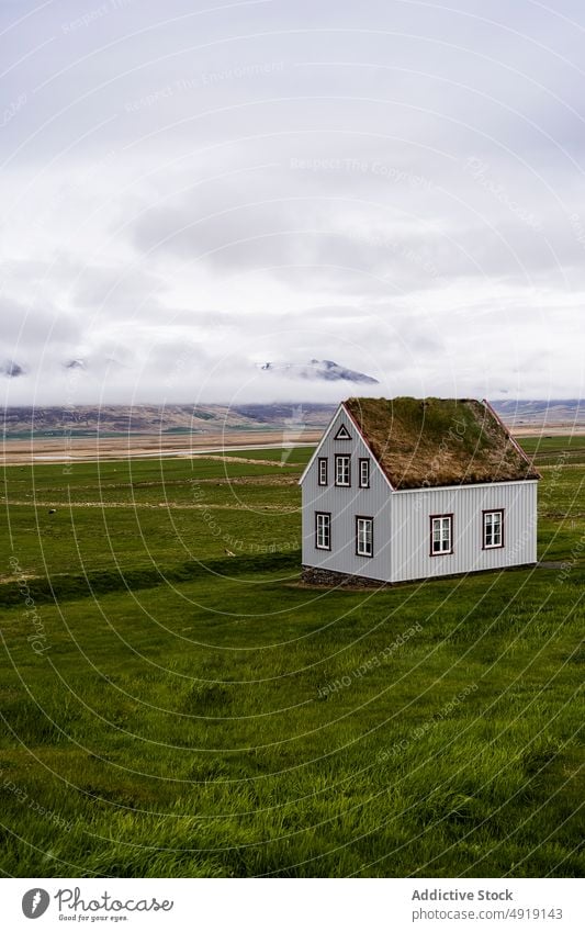 Nordic house located in countryside building nordic field grass hill rural typical roof grassy cloudy construction terrain iceland environment property