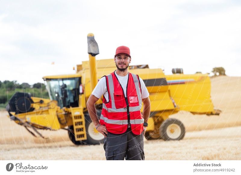 Man standing on field with combine harvester man farmer worker agriculture countryside portrait plantation industrial job labor occupation wheat beard