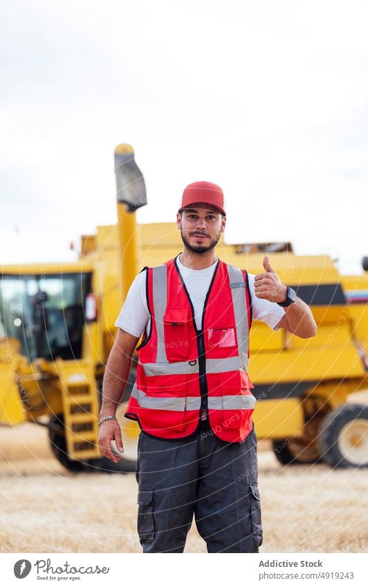 Man making thumb up gesture near combine harvester man worker like farmer agriculture countryside field agronomy job good workwear uniform male sign satisfied