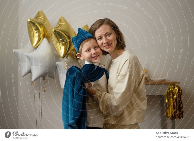 Mother holding little boy dressed up in a blue cap child party birthday happy fun mother son smile holiday celebration cute balloons star kiss childhood cape