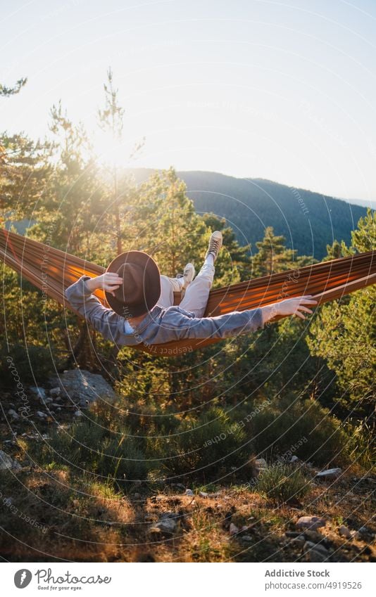 Faceless man resting in hammock in nature forest relax recreation woods leisure chill pastime headwear tree hat male summer plant sunshine journey summertime